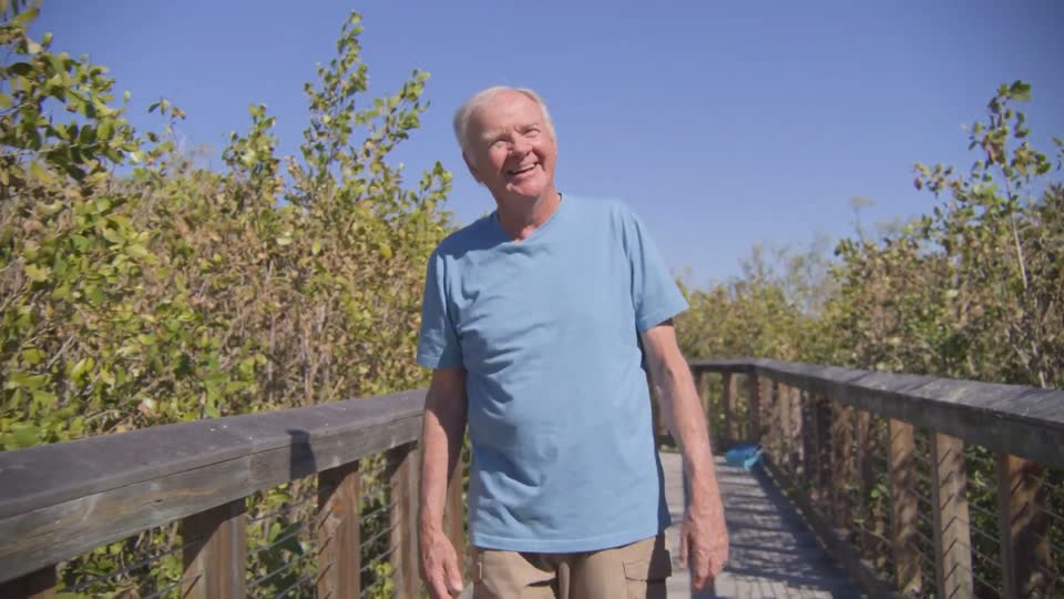 Man walking toward camera on a boardwalk